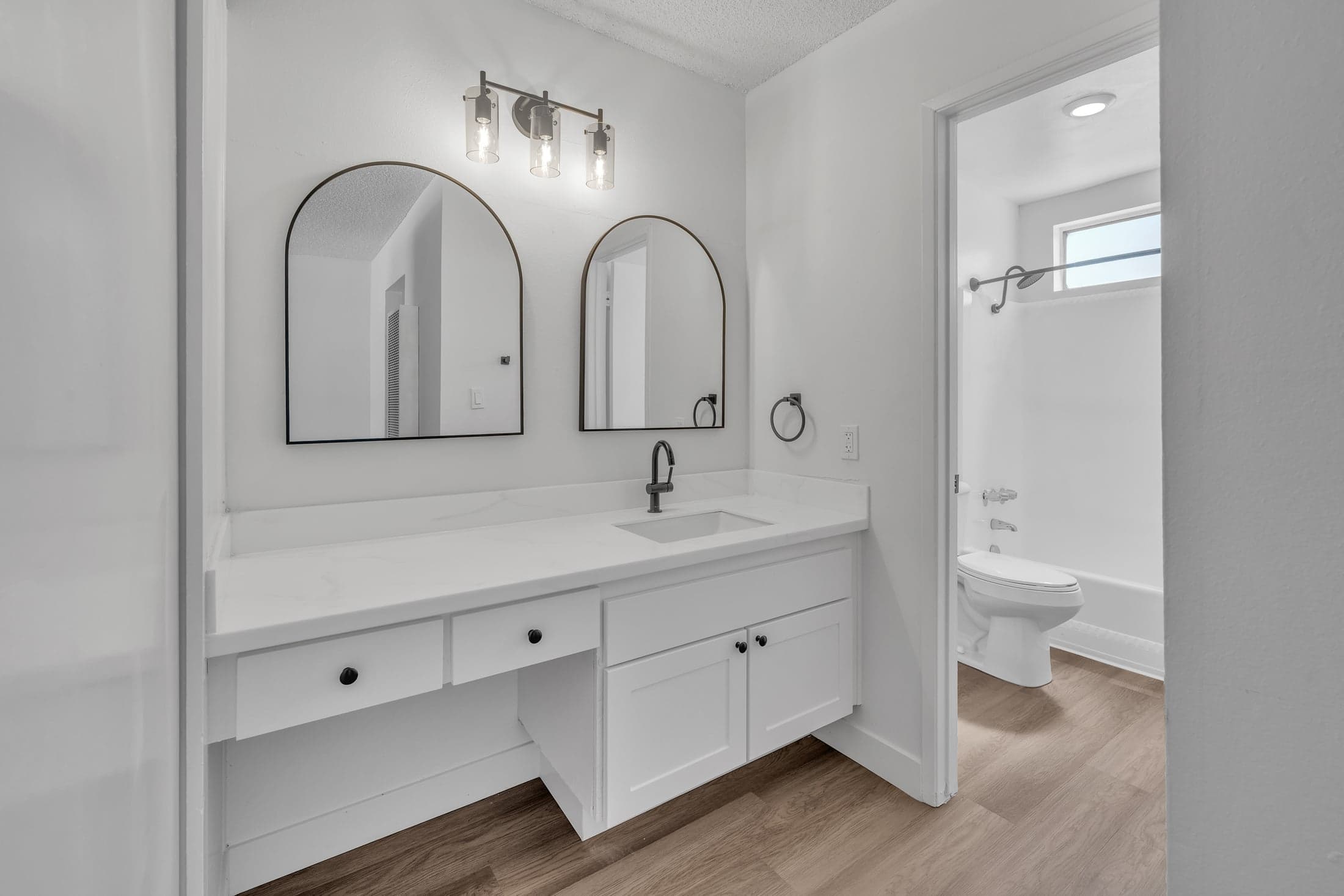 Paloma apartment bathroom with a double vanity and arched mirrors